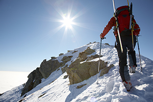 Male ski-climber climbing a snowy ridge; horizontal frame. Italian alps.
